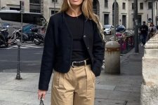 a quiet luxury outfit with a black t-shirt, a black cropped cardigan, beige high-waisted trousers, black shoes and a black bag