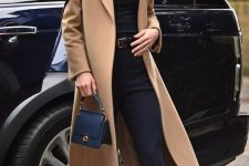 a quiet luxury outfit with a black turtleneck, flare trousers, black shoes, a camel midi coat and a small navy bag
