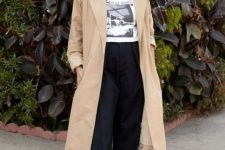 a relaxed outfit with a printed t-shirt, black baggy jeans, a tan trench and black Mary Jane shoes for spring