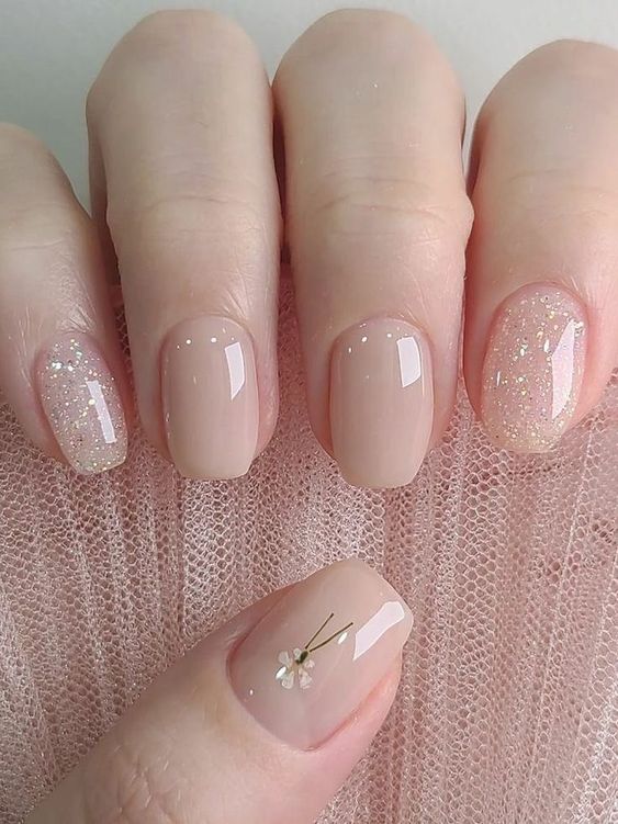 a short square nude manicure with glitter and a single dried flower is a super chic and delicate idea for spring