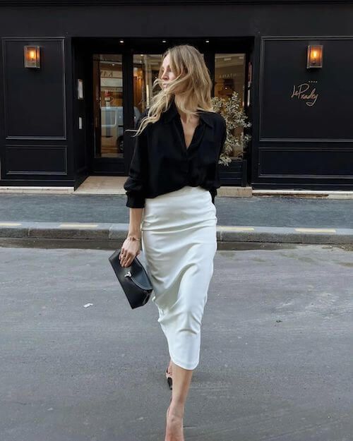 A simple and gorgeous quiet luxury look with a black button down, a creamy pencil midi, two tone shoes and a black clutch