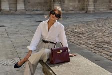 a stylish old money work look with a white button down, light grey pants, black slingbacks and a burgundy bag