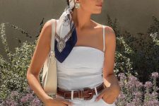 a stylish white romper with spaghetti straps, a brown belt, a creamy mini bag, statement earrings and a headband