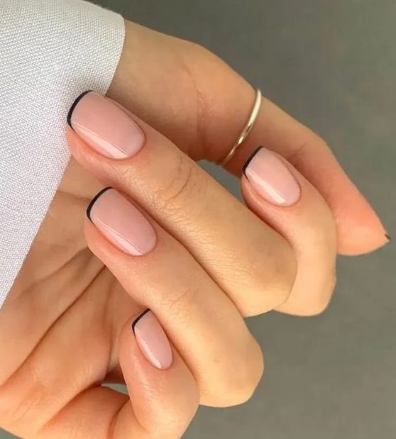 a super delicate and pretty barely there French manicure with nude nails and black tips
