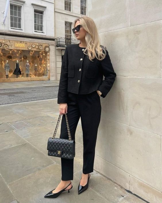 a total black look with a cropped blazer with accented buttons, cropped pants, slingbacks and a bag with chain