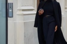 a total black outfit with a turtleneck, trousers, boots, a midi coat, a black belt and a small bag