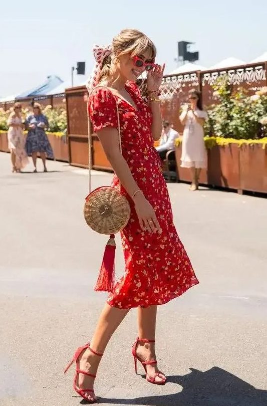 a vintage-styled red floral midi dress with short sleeves and a V-neckline, red heels and a straw bag