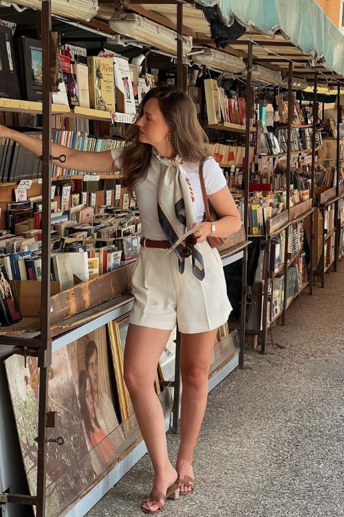 A white fitting t shirt, creamy cropped shorts, a brown belt and brown slippers, a small brown bag and a neck tie