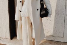 a white sweater, white pants, a white coat with black buttons and a black bag plus black booties