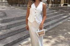 a white waistcoat, a white slip maxi skirt, white slippers and a small bag for an effortless old money summer look