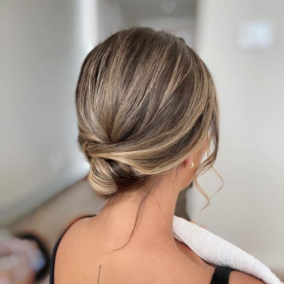 an elegant and sleek wrapped low updo with a sleek top and face-framing hair is perfect for a special occasion