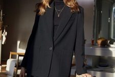 an elegant total black outfit with a turtleneck, black leather pants, an oversized black blazer with pockets and layered necklaces