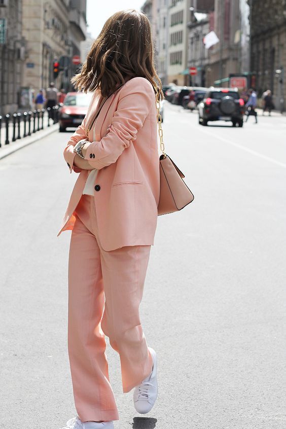 an everyday work look with a peachy pink pantsuit, a white t-shirt, white sneakers and a tan bag with chain