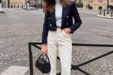 an old money outfit with a white turtleneck, creamy jeans, a navy cropped blazer, black shoes and a black bag
