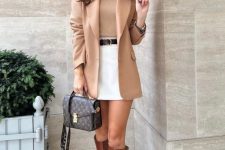 an old money work outfit with a beige turtleneck and a blazer, a white mini, brown knee boots, a brown printed bag