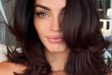 gorgeous medium-length dark brown hair styled with a butterfly haircut and with volume and waves is amazing
