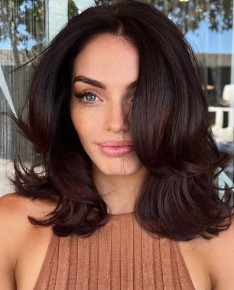 Gorgeous medium length dark brown hair styled with a butterfly haircut and with volume and waves is amazing
