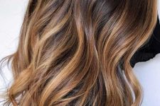 long and volumetric hair from dark brunette to caramel and honey blonde ombre with waves, is a very chic and romantic idea