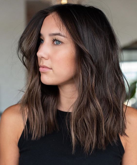Medium length dark brown hair of a cold shade, with slight balayage for an accent and messy texture is a super cool idea