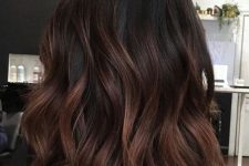 medium-length dark brown hair with copper balayage that gives it dimension and interest, and shaggy layers make it cooler