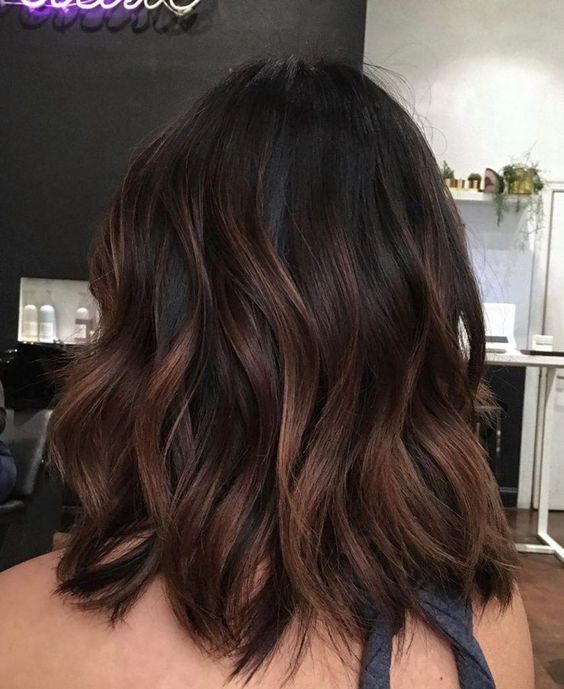 medium-length dark brown hair with copper balayage that gives it dimension and interest, and shaggy layers make it cooler