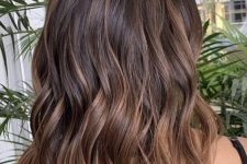 medium-length deep brunette wavy hair with chestnut balayage and waves is a cool idea to rock any time