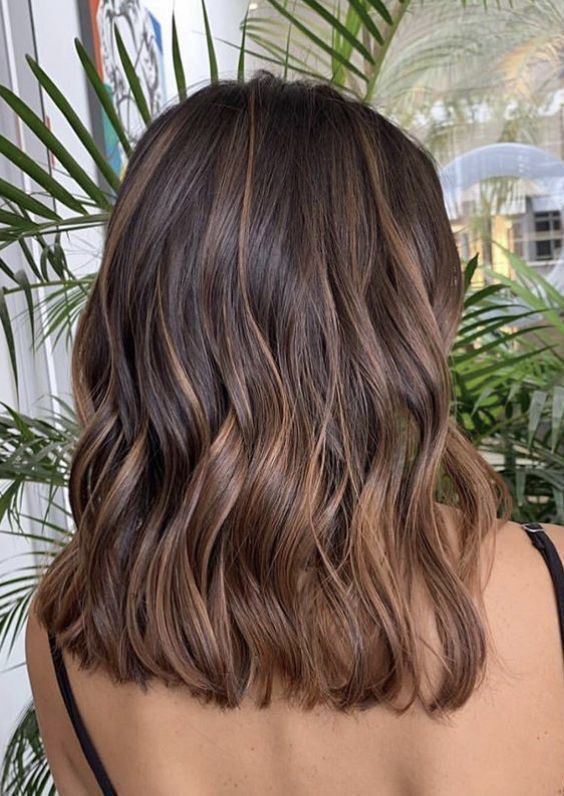 Medium length deep brunette wavy hair with chestnut balayage and waves is a cool idea to rock any time
