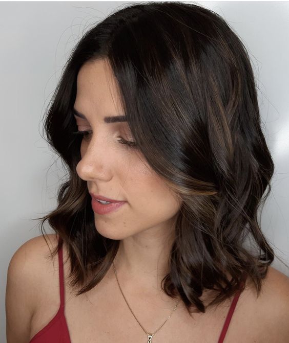 Shoulder length dark brown hair with caramel balayage that catches an eye, gives dimension, and waves add a soft touch