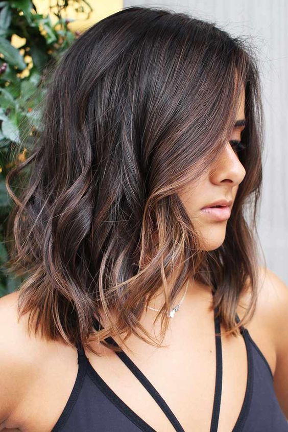 Shoulder length dark brown hair with copper highlights and messy waves is a relaxed and cool solution to try right now