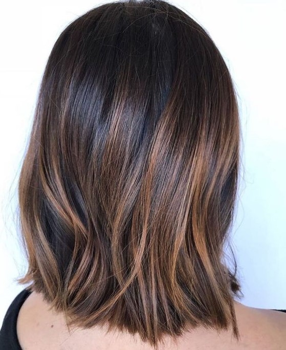 Very dark brown straight long bob with delicate caramel highlights that add eye catchiness and interest to the look