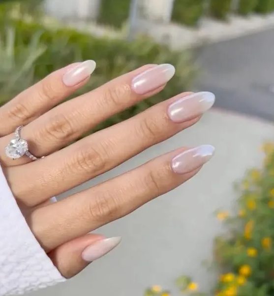 very subtle and delicate blush chrome nails of an almond shape are a cool solution for a bride, they look very soft