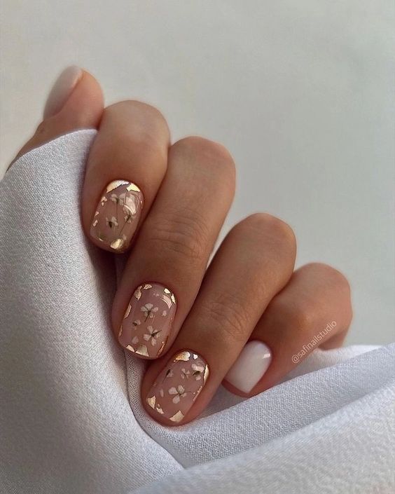 a beautiful glam spring wedding manicure with white flowers and gold leaf is amazing for any bride who loves a bit of shine