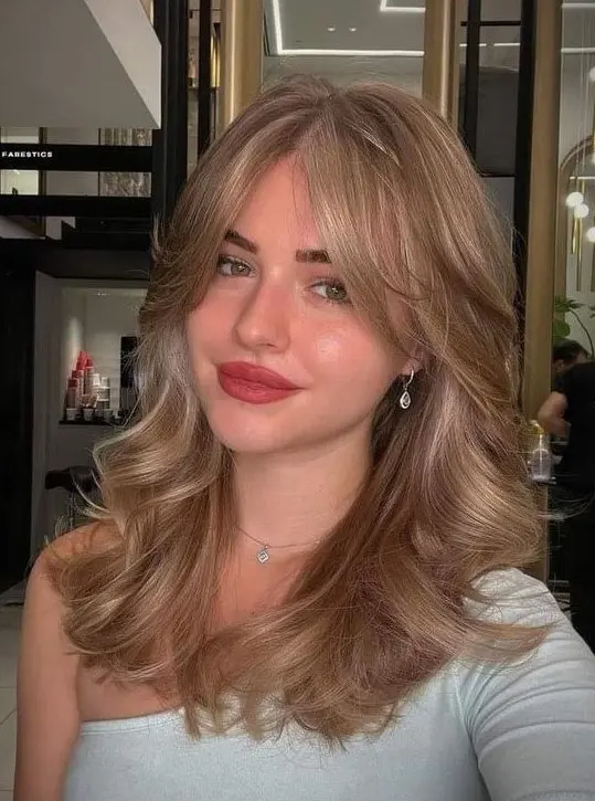 18 a gorgeous bronde wavy hairstyle done on a butterfly haircut, with curtain bangs, is adorable and very chic
