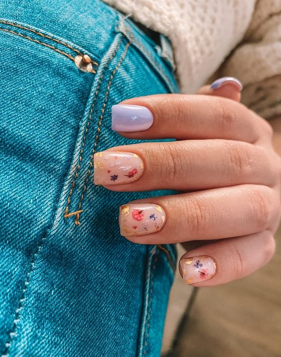 a nude and lilac manicure with nude nails accented with gold leaf and colorful dried blooms looks very spring-like