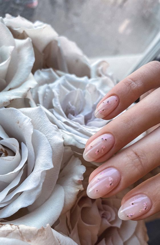 a subtle blush manicure with semi sheer gel and light pink dried blooms and gold glitter touches is amazing for spring