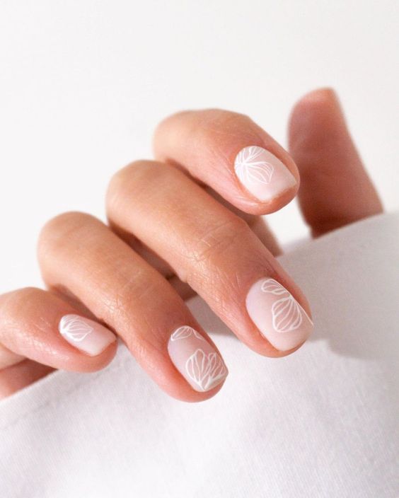 dreamy spring wedding nails of a soft matte nude shade, with painted wihte flowers on them, are amazing