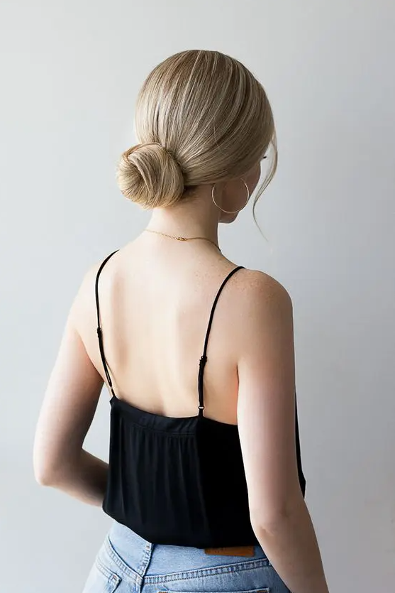 a classic twisted low bun with a sleek top and some face-framing locks is a cool hairstyle to rock