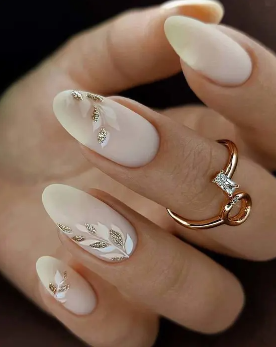 matte milky nails accented with white and blush botanical patterns and gold glitter are amazing for a glam bride