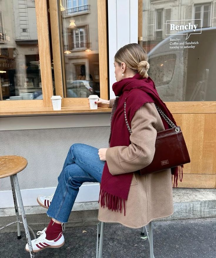 a beautiful look with a tan coat, a cherry red scarf and a bag, blue jeans and shoes plus burgundy socks