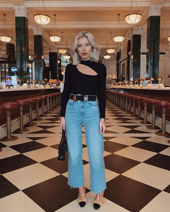 A bold and sexy spring outfit with a black cutout long sleeve top, blue cropped jeans, two tone shoes and a black bag
