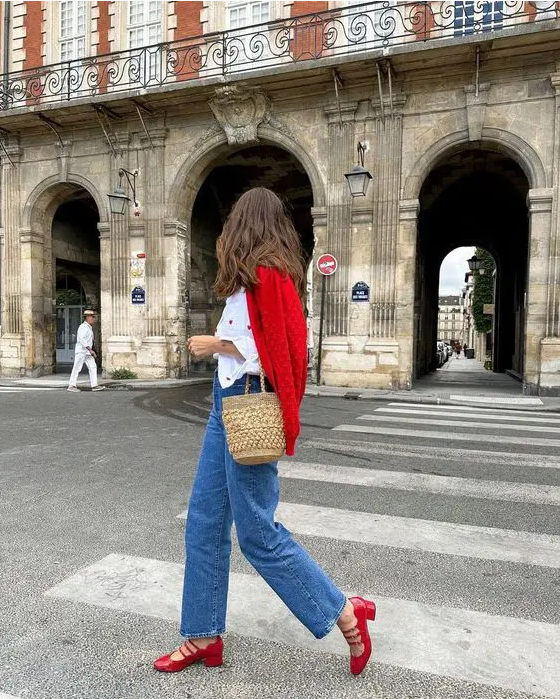 a classic Parisian look with a white shirt, blue jeans, red Mary Jane shoes, a red cardigan and a basket bag