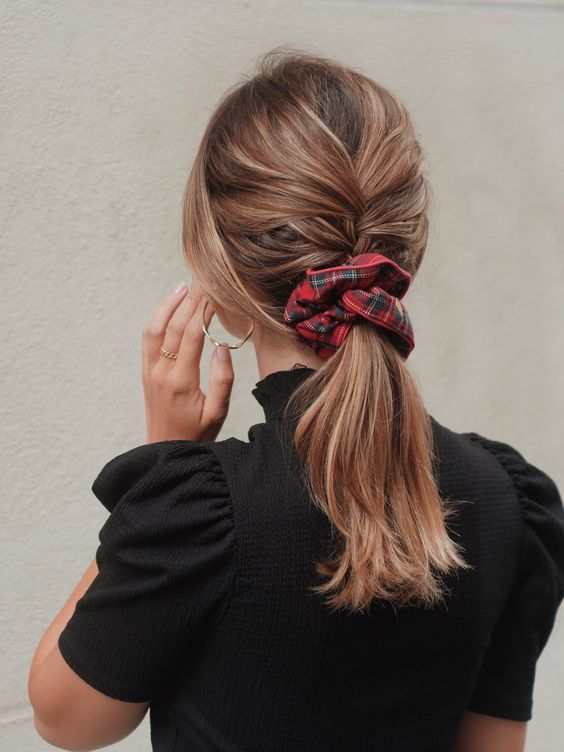 a classy braid into ponytail with face-framing hair and a plaid red scrunchie for a Christmas party