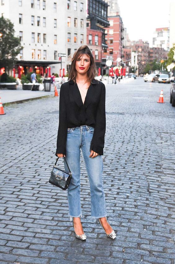 a classy night out look with a black blouse, blue jeans, silver pumps and a black embossed bag