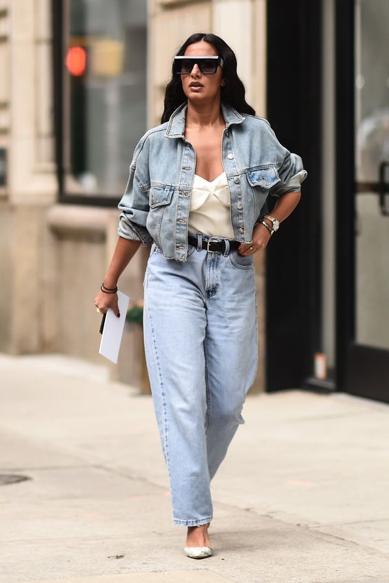 a classy spring look with a white bustier top, blue straight jeans, neutral shoes, a cropped denim jacket and a black belt