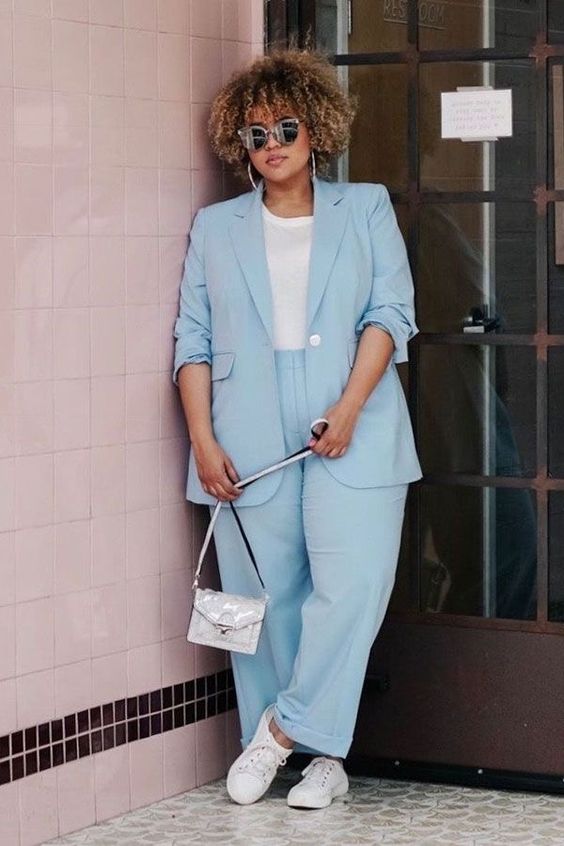 a cool outfit with a pastel blue power suit, a white t-shirt, white sneakers and a small bag plus statement earrings