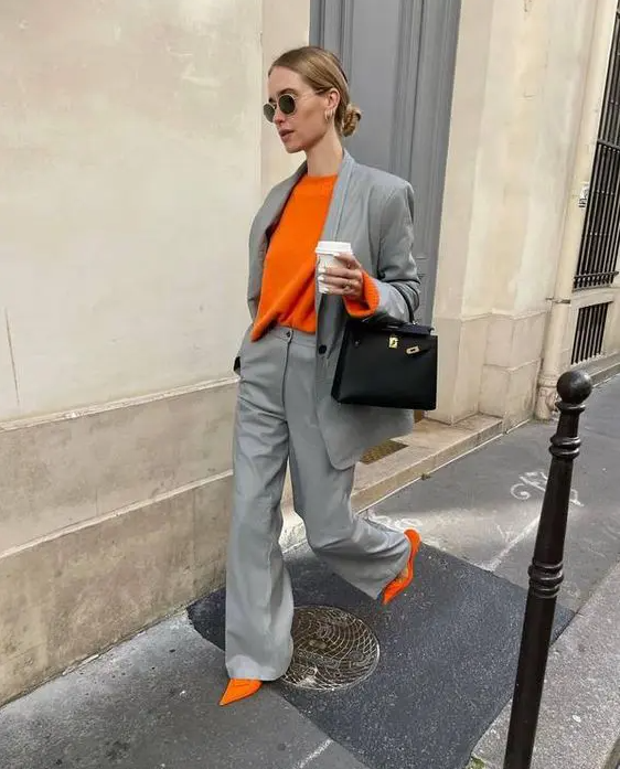 a grey pantsuit, an orange long sleeve top, orange shoes and a black bag are a perfect spring work outfit