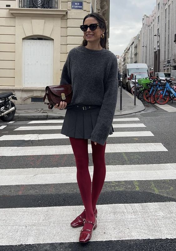 a grey sweater, a grey plated mini skirt, cherry red tights and lacquer shoes plus a burgundy bag are lovely