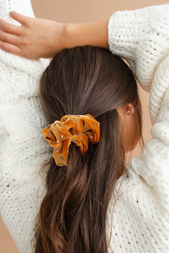 a half updo with an orange velvet floral scrunchie is a cool hairstyle for every day, the scrunchie will add color