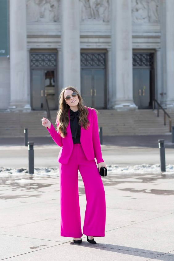 a hot pink power suit, a black button down, black shoes and a small bag are a lovely and bold look for a special occasion