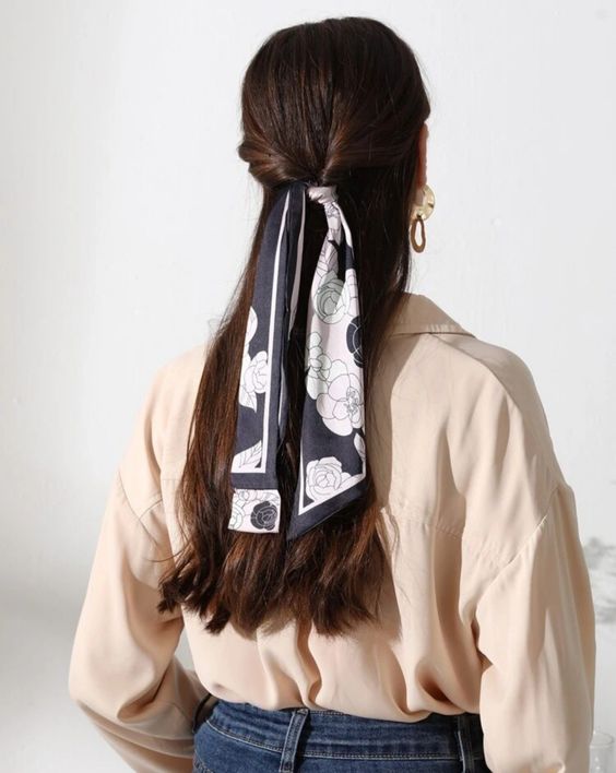 a long twisted half updo with a sleek top and a black and white printed scarf as an accent is a stylish and catchy idea